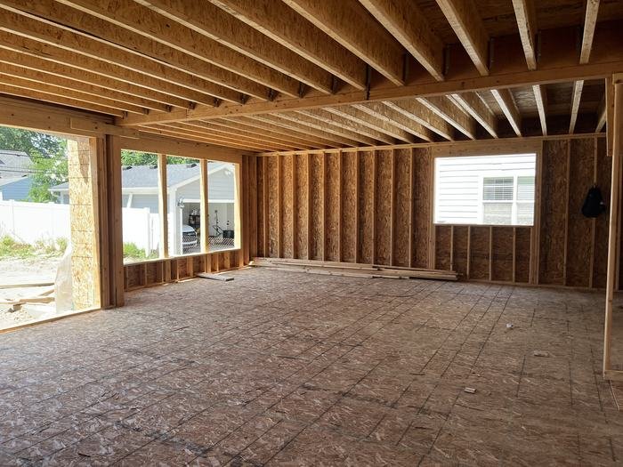 Open main floor framing with large window openings and floor joists overhead